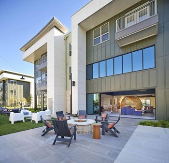 a patio with chairs and a table in front of a building